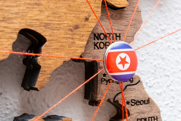 North Korea flag on the pushpin with red thread showed the paths of movement or areas of influence...