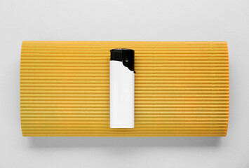 Stylish small pocket lighter with yellow corrugated fiberboard on white background, top view