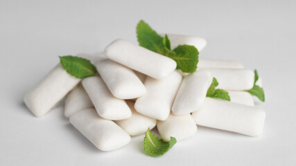 Tasty chewing gums and mint leaves on white background