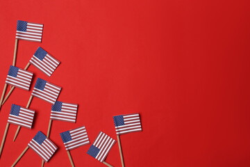 Small paper flags of USA on red background, flat lay. Space for text