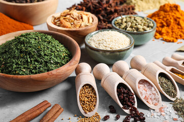 Scoops with different spices on gray marble table