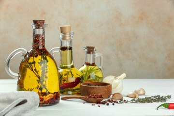 Obraz na płótnie Canvas Cooking oil with different spices and herbs in jugs on white wooden table. Space for text
