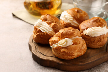 Delicious profiteroles filled with cream on grey table, closeup. Space for text