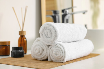 Rolled soft towels on white table in bathroom