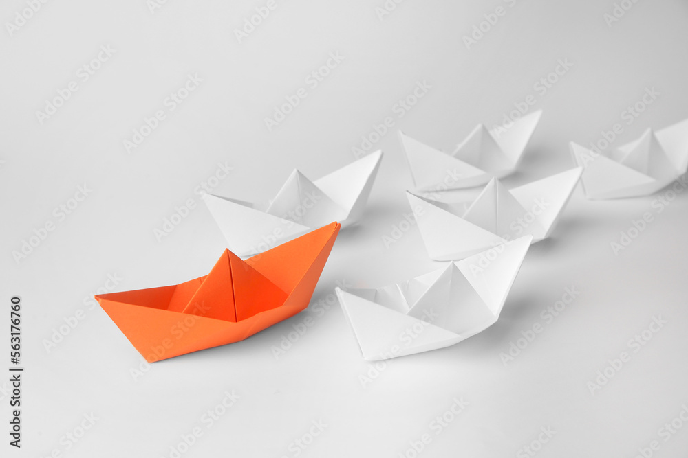 Wall mural Group of paper boats following orange one on white background. Leadership concept