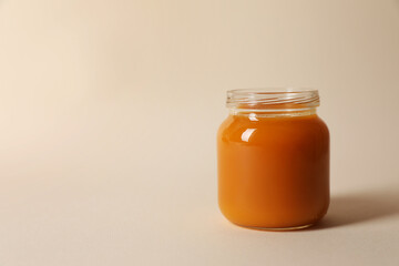 Jar with healthy baby food on beige background. Space for text