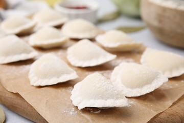 Fototapeta na wymiar Raw dumplings (varenyky) with tasty filling on light grey table, closeup
