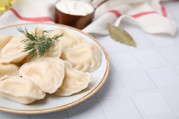 Fototapeta na wymiar Cooked dumplings (varenyky) with tasty filling and dill on white table, closeup. Space for text