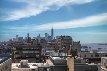 Obraz premium Lower Manhattan skyline looking south next to Hudson River, sunny, blue sky, clouds, brick and steel buildings, rooftops, nobody