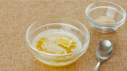 Melted butter in a glass bowl, and garlic seasoning in a glass bowl close-up