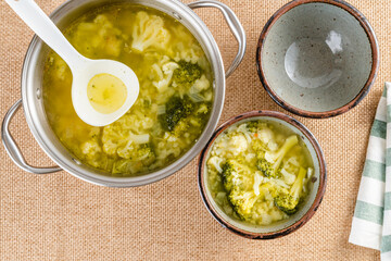 Serving soup. Cauliflower broccoli soup in a cooking pot close-up on a table, flat lay, copy space