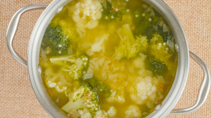 Cooking pot with cauliflower broccoli soup close-up on a table on a rustic background