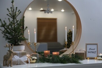 Mirror over shelf with Christmas decor in room. Interior design