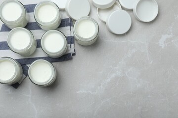 Tasty yogurt in glass jars on light grey marble table, flat lay. Space for text