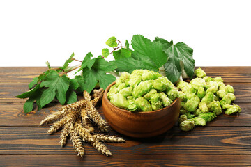 Fresh hop flowers and wheat ears on wooden table against white background