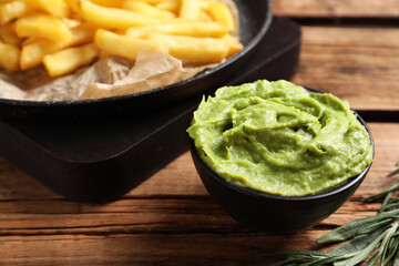 French fries, avocado dip and rosemary served on wooden table, closeup