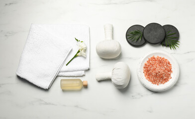 Spa bags, pink salt and essential oil on white marble table, flat lay