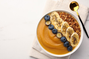 Delicious smoothie bowl with fresh blueberries, banana and granola on white table, flat lay. Space for text