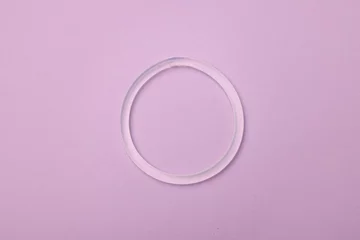 Poster Diaphragm vaginal contraceptive ring on lilac background, top view © New Africa