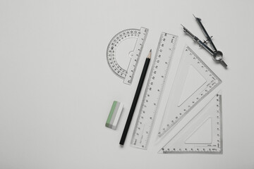 Different rulers and compass on yellow background, flat lay. Space for text