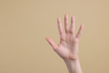 Woman giving high five on light brown background, closeup. Space for text