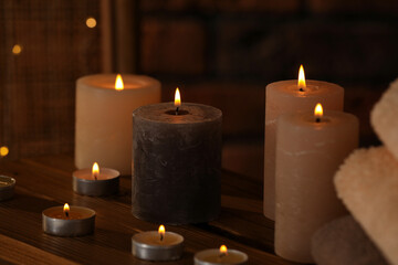 Spa composition with burning candles on wooden table in wellness center, closeup