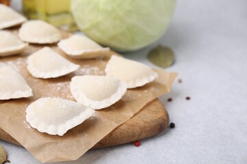 Raw dumplings (varenyky) with tasty filling on light grey table, closeup. Space for text