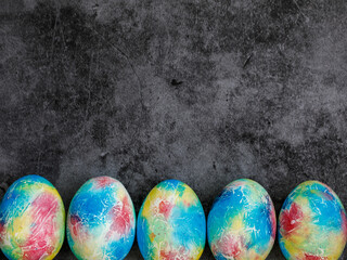 Colorful handmade Easter eggs painted like Earth on black marble background with copy space for Easter text message. Minimal happy Easter holiday conceprt. Top view flat lay, border frame