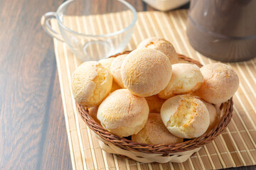 cheese breads in wooden basket with cup of coffee, concept of traditional brazilian meal, afternoon...