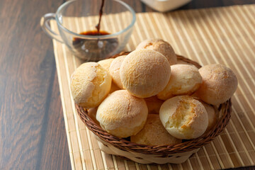 cheese breads in wooden basket with cup of coffee, concept of traditional brazilian meal, afternoon...