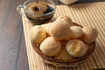 cheese breads in wooden basket with cup of coffee, concept of traditional brazilian meal, afternoon snack