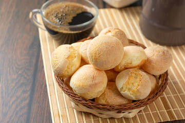 cheese breads in wooden basket with cup of coffee, concept of traditional brazilian meal, afternoon snack