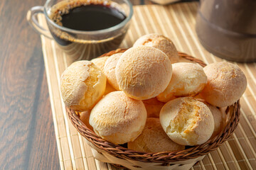 cheese breads in wooden basket with cup of coffee, concept of traditional brazilian meal, afternoon snack