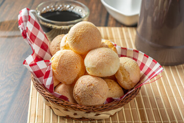 cheese breads in wooden basket with cup of coffee, concept of traditional brazilian meal, afternoon snack