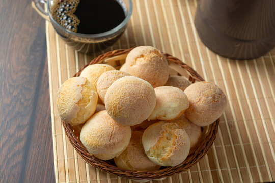 cheese breads in wooden basket with cup of coffee, concept of traditional brazilian meal, afternoon snack