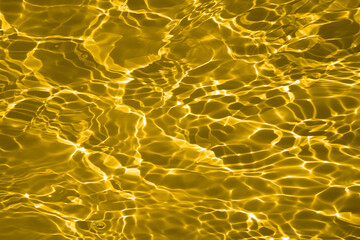 Defocus blurred transparent gold colored clear calm water surface texture with splashes and...