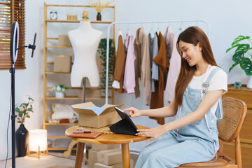 Online shopping concept, Asian women check sales volume on tablet after live stream selling clothes