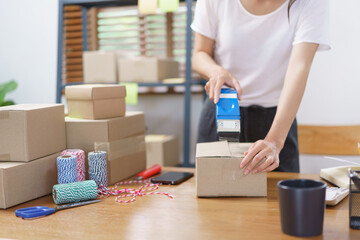 Online business concept, Asian business women packing product into parcel box and sealing with tape
