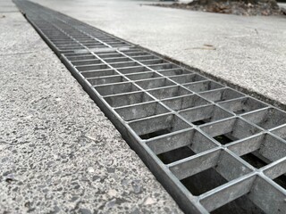 Obraz premium Closeup, metal cover of street water drain. Against the background of paving slabs made from gray granite