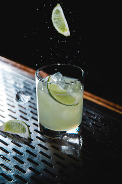 Classic Margarita with salt and lime falling around the glass on bar