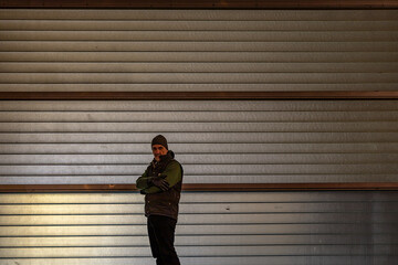 Copenhagen, Denmark  A man stands against an illuminated garage door at night.