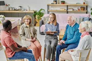 Senior people talking to psychotherapist during psychotherapy session in nursing home