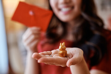 Close up of woman holding golden rabbit and ang pao during Chinese New Year celebration.