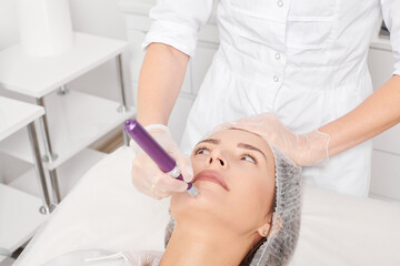 Beautician makes mesotherapy injection for rejuvenation woman face, procedure in beauty salon