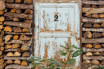 une vieille porte étrange dans un tas de bois. Une ancienne porte avec un numéro dans une pile de bois de chauffage. Une porte de cabane.
