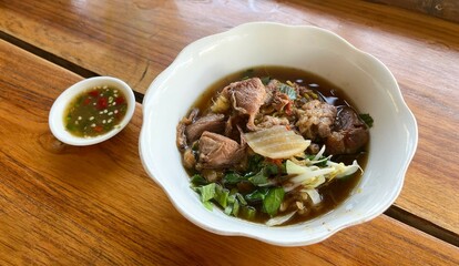 Stewed Pork Noodles with Thai Style Soup boat noodles Selective focus. Placed on wooden table. Top view.