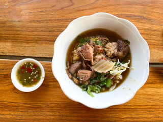 Stewed Pork Noodles with Thai Style Soup boat noodles Selective focus. Placed on wooden table. Top view.