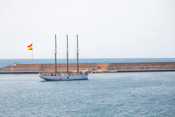 A three-masted sailing ship enters the Spanish Bay with lowered sails.