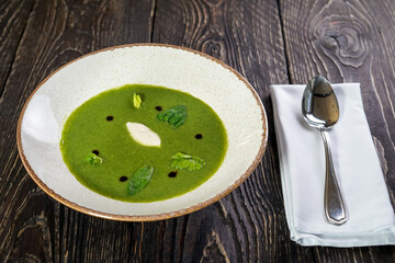spinach cream soup in a plate on a background with willow macro
