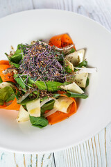 salad with spinach, pear and quinoa in a plate on a white background, vertical photo
